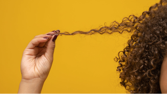 Woman styles curly hair with heatless hair curlers, achieving natural, healthy curls through gentle styling