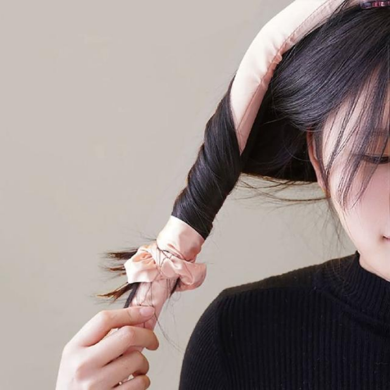 Person styling hair with a heatless hair curler (in-action step for holiday-perfect curls)