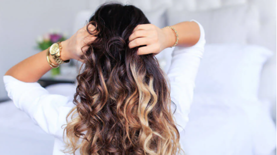 A woman styles lush, beautiful curls—created safely with a heatless hair curler (the core of the ultimate guide).