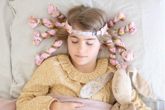 This child uses foam heatless hair curlers for an overnight transformation, waking up to bouncy curls without any heat damage.