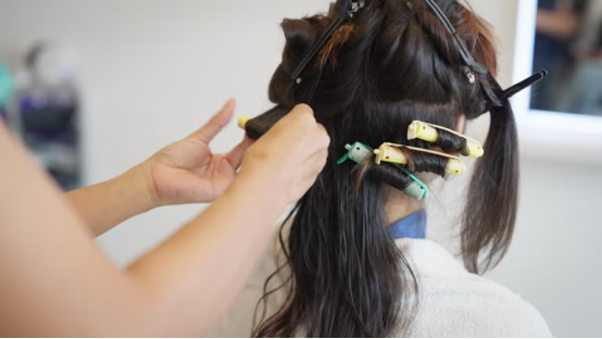 A stylist applying soft curlers to hair, demonstrating the gentle, non-damaging application of a heatless hair curler.